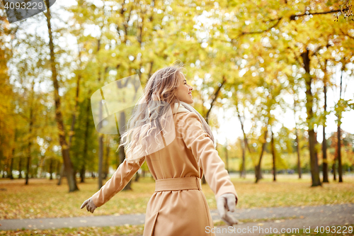 Image of beautiful happy young woman walking in autumn park