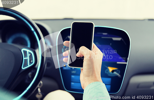 Image of close up of male hand with smartphone driving car