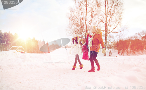 Image of happy family in winter clothes walking outdoors