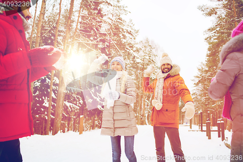 Image of happy friends playing snowball in winter forest