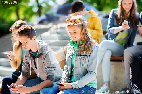 Image of teenage friends with smartphones outdoors