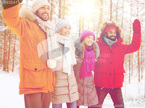 Image of group of friends waving hands in winter forest