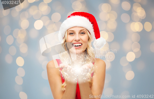 Image of happy woman in santa hat holding fairy dust 