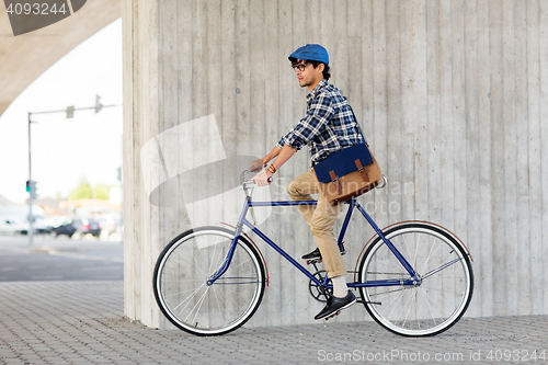 Image of young hipster man with bag riding fixed gear bike