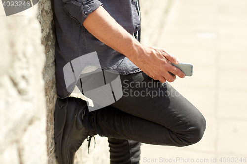 Image of close up of man with smartphone at stone wall