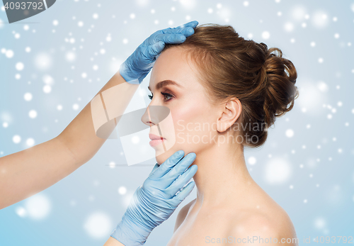 Image of surgeon or beautician hands touching woman face