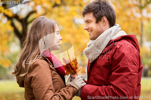 Image of happy couple with maple leaves in autumn park