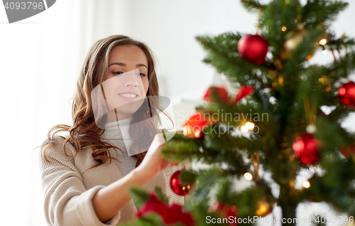 Image of happy young woman decorating christmas tree