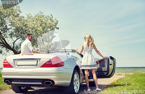 Image of happy man and woman near cabriolet car at sea