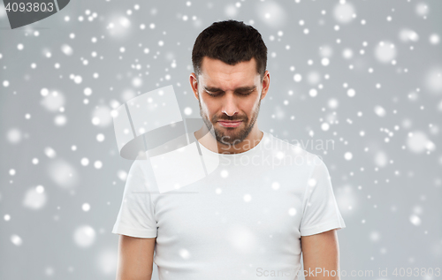 Image of unhappy young man over snow background