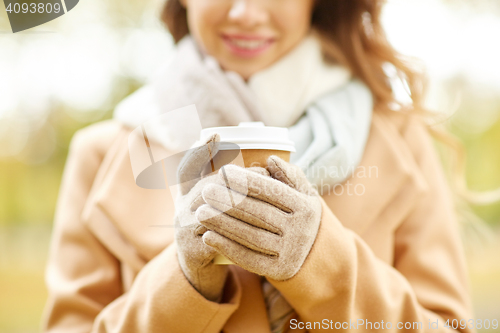 Image of close up of happy woman with coffee in autumn park