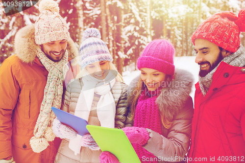 Image of smiling friends with tablet pc in winter forest