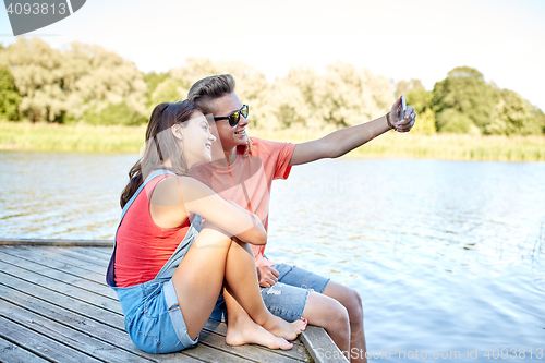 Image of happy teenage couple taking selfie on smartphone