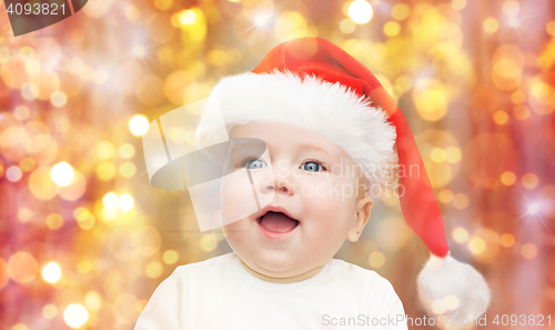 Image of baby boy in christmas santa hat over blue lights