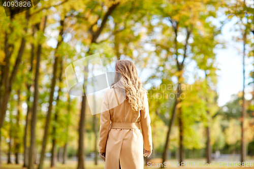 Image of beautiful young woman walking in autumn park