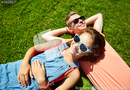 Image of happy teenage couple lying on grass at summer