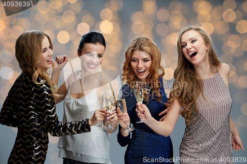 Image of happy women clinking champagne glasses over lights