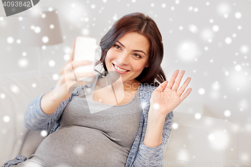 Image of happy pregnant woman with smartphone at home