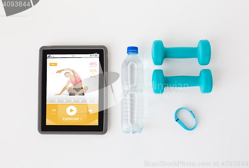 Image of tablet pc, dumbbells, fitness tracker and bottle