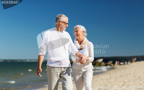 Image of happy senior couple holding hands on summer beach