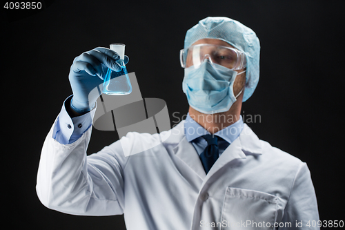 Image of scientist in mask holding flask with chemical