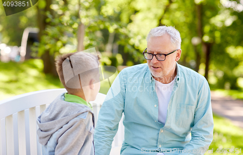 Image of grandfather and grandson talking at summer park