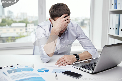 Image of stressed businessman with papers in office