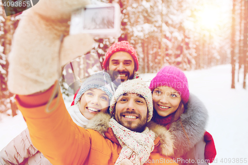 Image of smiling friends with camera in winter forest