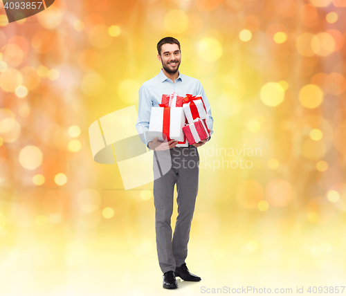 Image of happy young man holding gift boxes