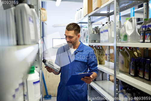 Image of auto mechanic with oil and clipboard at car shop