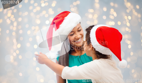 Image of happy mother and little girl in santa hats