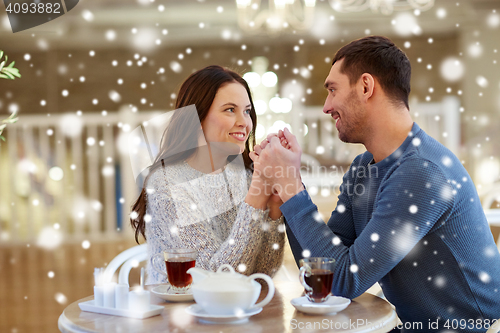 Image of happy couple with tea holding hands at restaurant