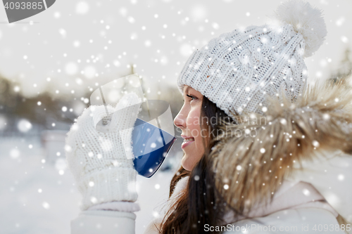 Image of happy young woman with tea cup outdoors in winter