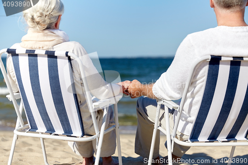 Image of senior couple sitting on chairs at summer beach