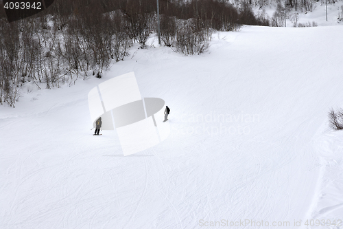 Image of Skier and snowboarder on ski slope at gray winter day