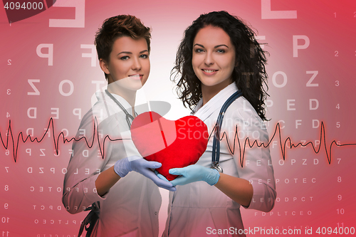 Image of Two woman doctor holding a red heart