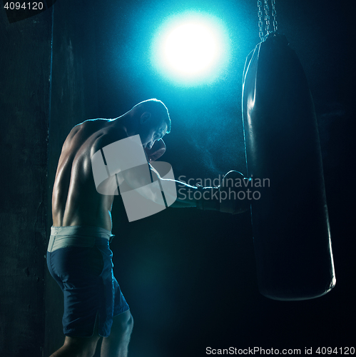 Image of Male boxer boxing in punching bag