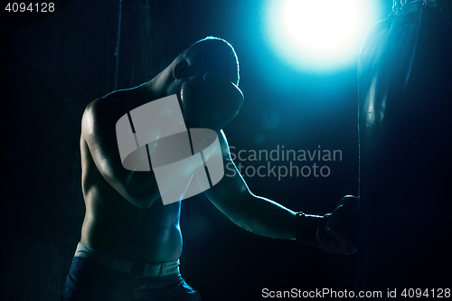 Image of Male boxer boxing in punching bag