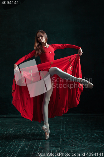 Image of Ballerina posing in pointe shoes at black wooden pavilion