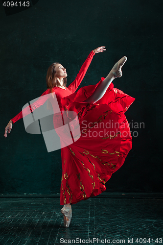 Image of Ballerina posing in pointe shoes at black wooden pavilion