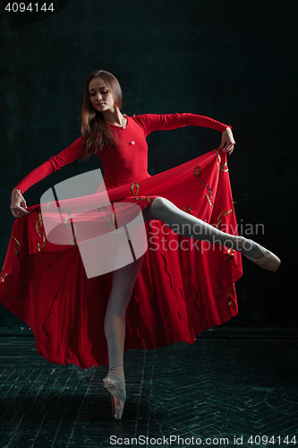 Image of Ballerina posing in pointe shoes at black wooden pavilion