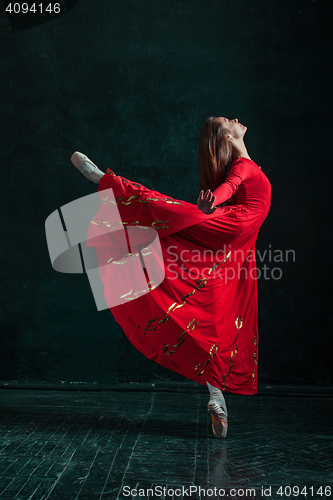 Image of Ballerina posing in pointe shoes at black wooden pavilion