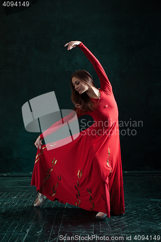 Image of Ballerina posing in pointe shoes at black wooden pavilion