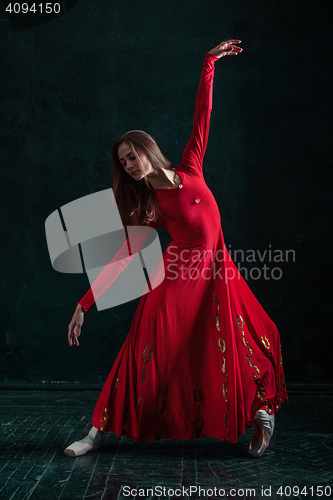 Image of Ballerina posing in pointe shoes at black wooden pavilion