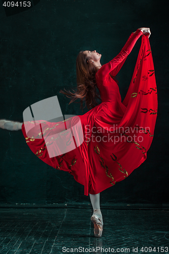 Image of Ballerina posing in pointe shoes at black wooden pavilion