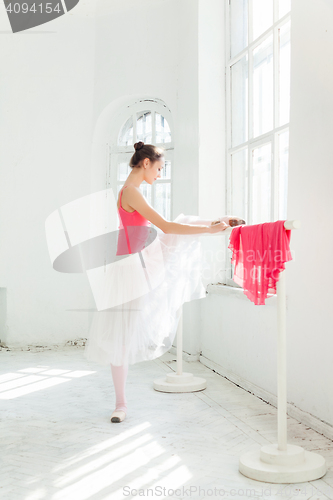 Image of Ballerina posing in pointe shoes at white wooden pavilion