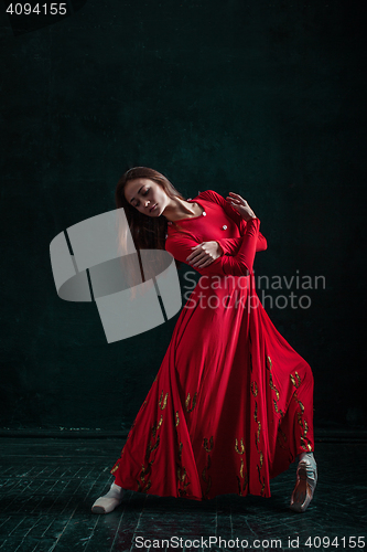 Image of Ballerina posing in pointe shoes at black wooden pavilion