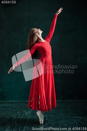 Image of Ballerina posing in pointe shoes at black wooden pavilion