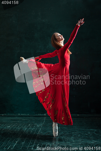 Image of Ballerina posing in pointe shoes at black wooden pavilion