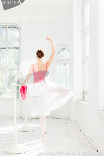 Image of Ballerina posing in pointe shoes at white wooden pavilion